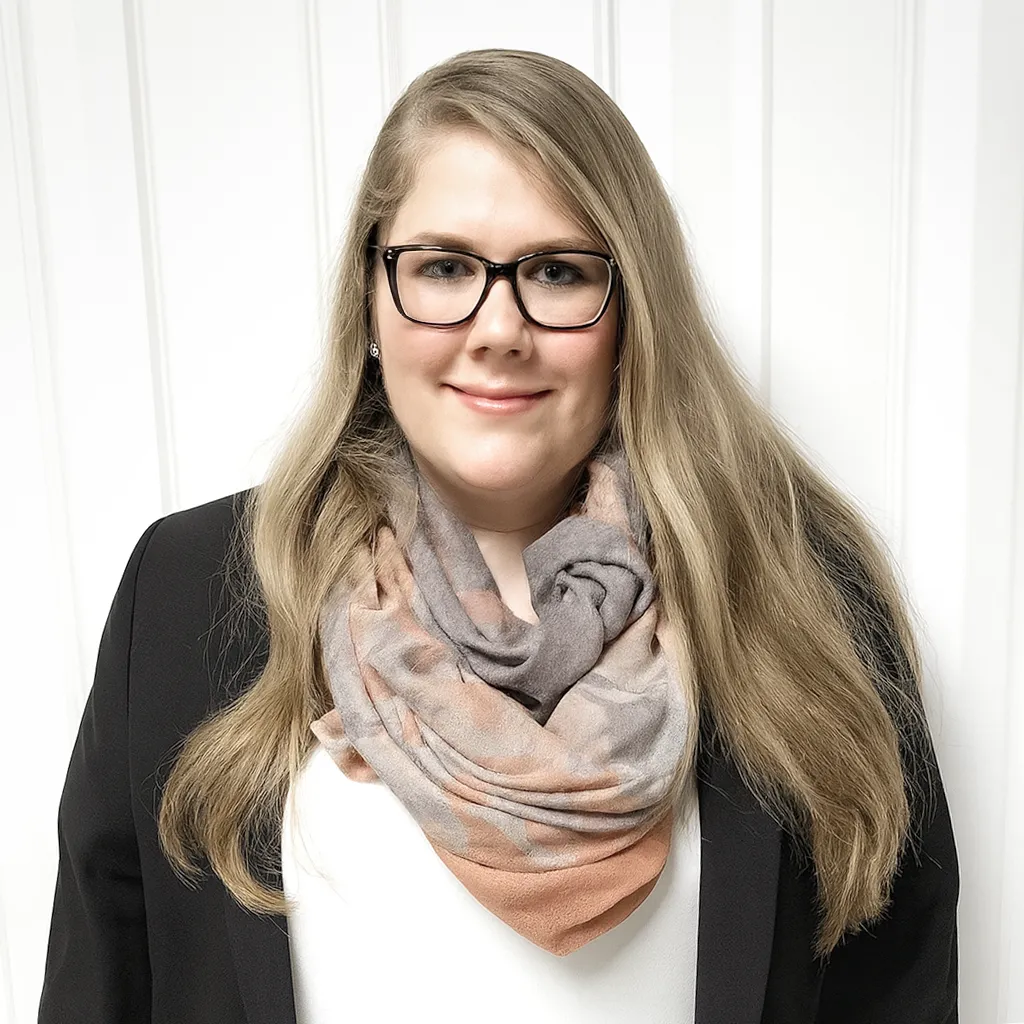 Sonja Achten steht vor eine Wand und blickt lächelnd in die Kamera